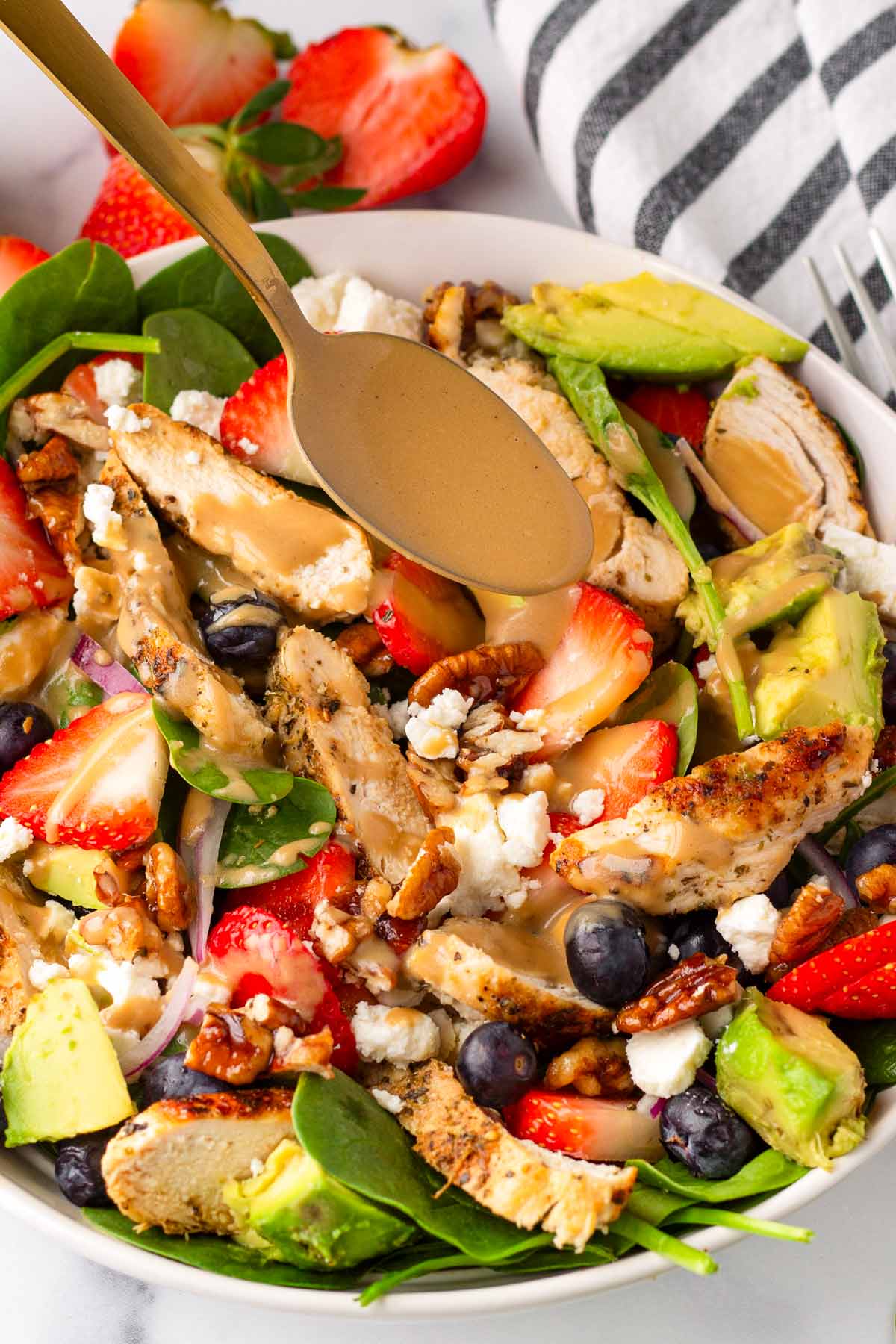 adding creamy balsamic dressing from a spoon to the salad bowl