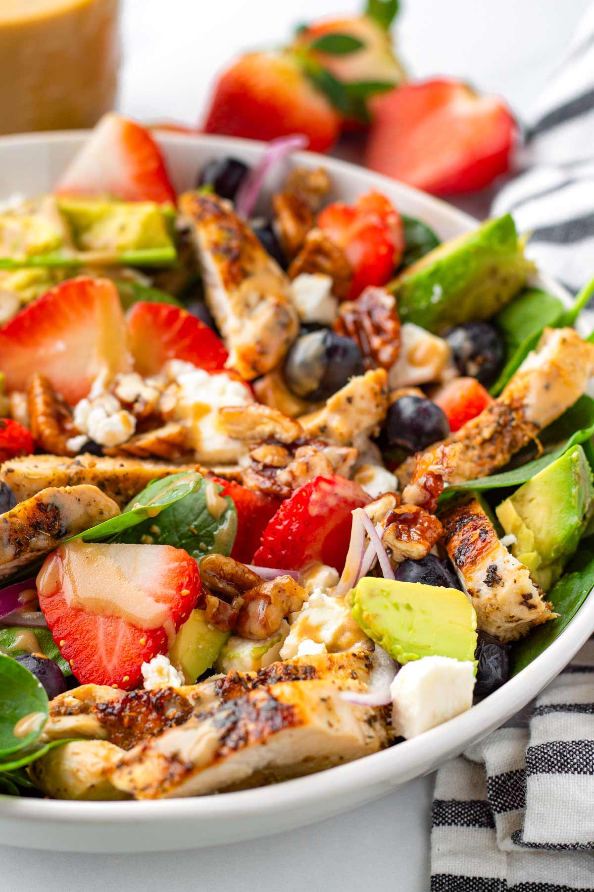 side view of bowl of chicken salad with avocado, spinach, and seasonal ingredients
