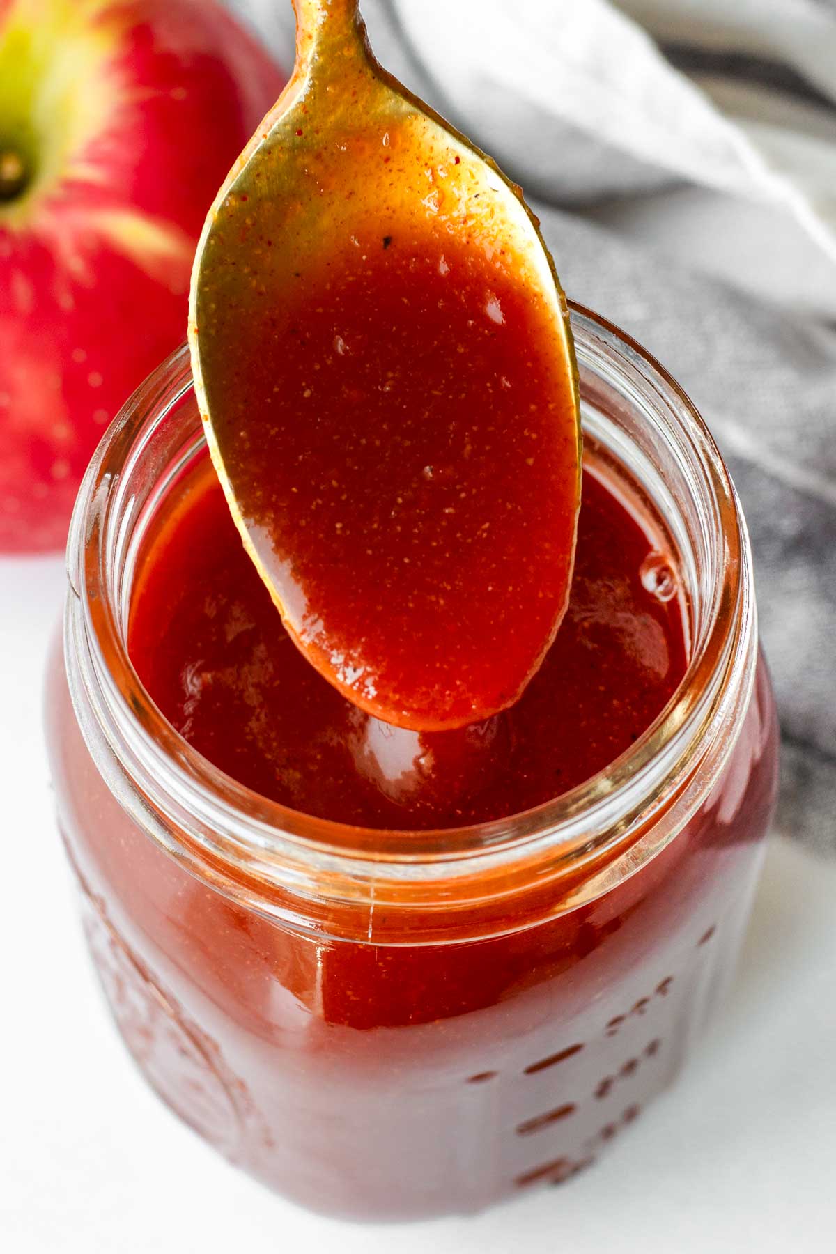 a spoonful of apple cider bbq sauce from a mason jar