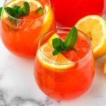 two glasses of strawberry lemonade with lemon garnish