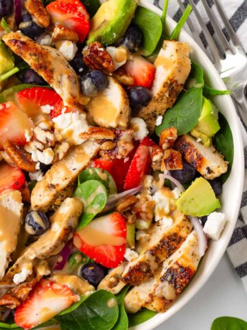 bowl of strawberry chicken salad with dressing and pecans