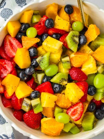 fruit salad with various colors arranged in a bowl with spoon