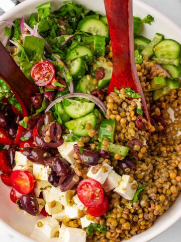 tossing mediterranean lentil salad with wooden spoons