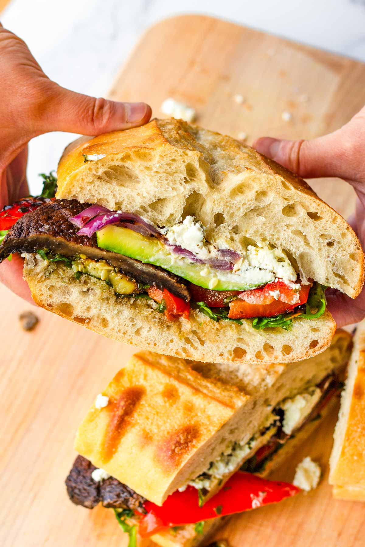 holding a grilled vegetable sandwich with goat cheese