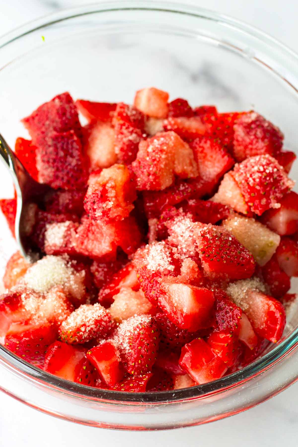 diced strawberries tossed with granulated sugar in a bowl