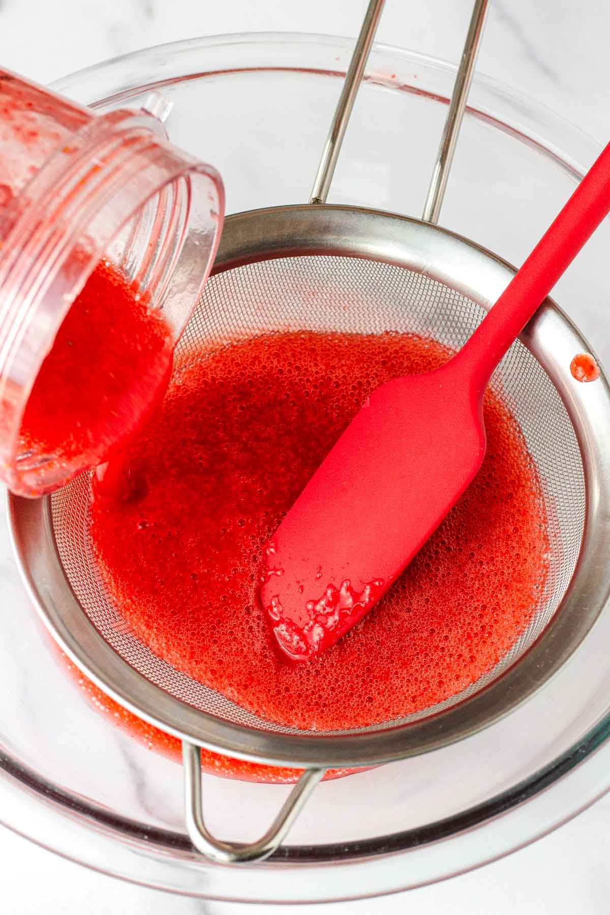 straining the strawberry puree through a sieve