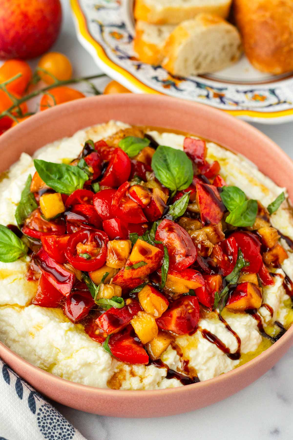 whipped burrata with peaches in a shallow pink bowl