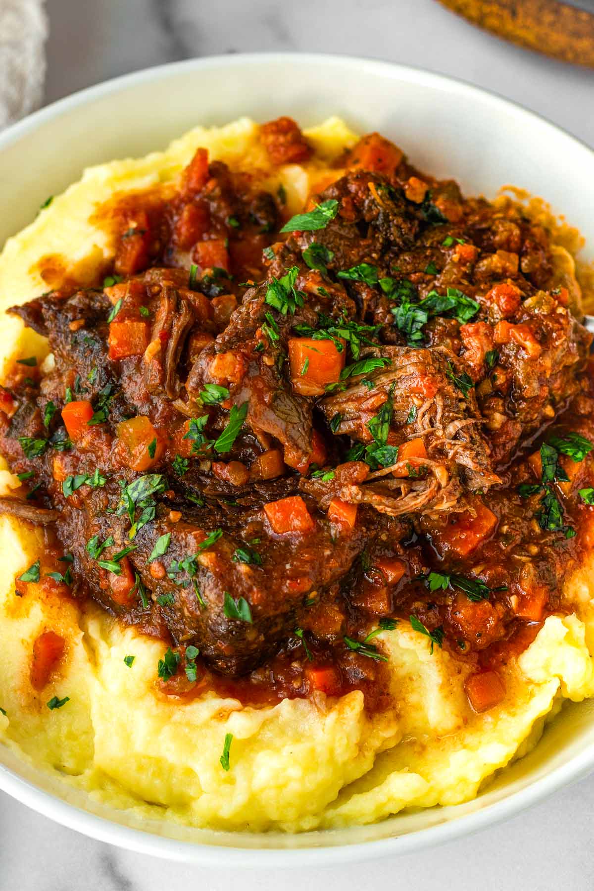 bowl with garnished italian pot roast served on top of mashed potatoes