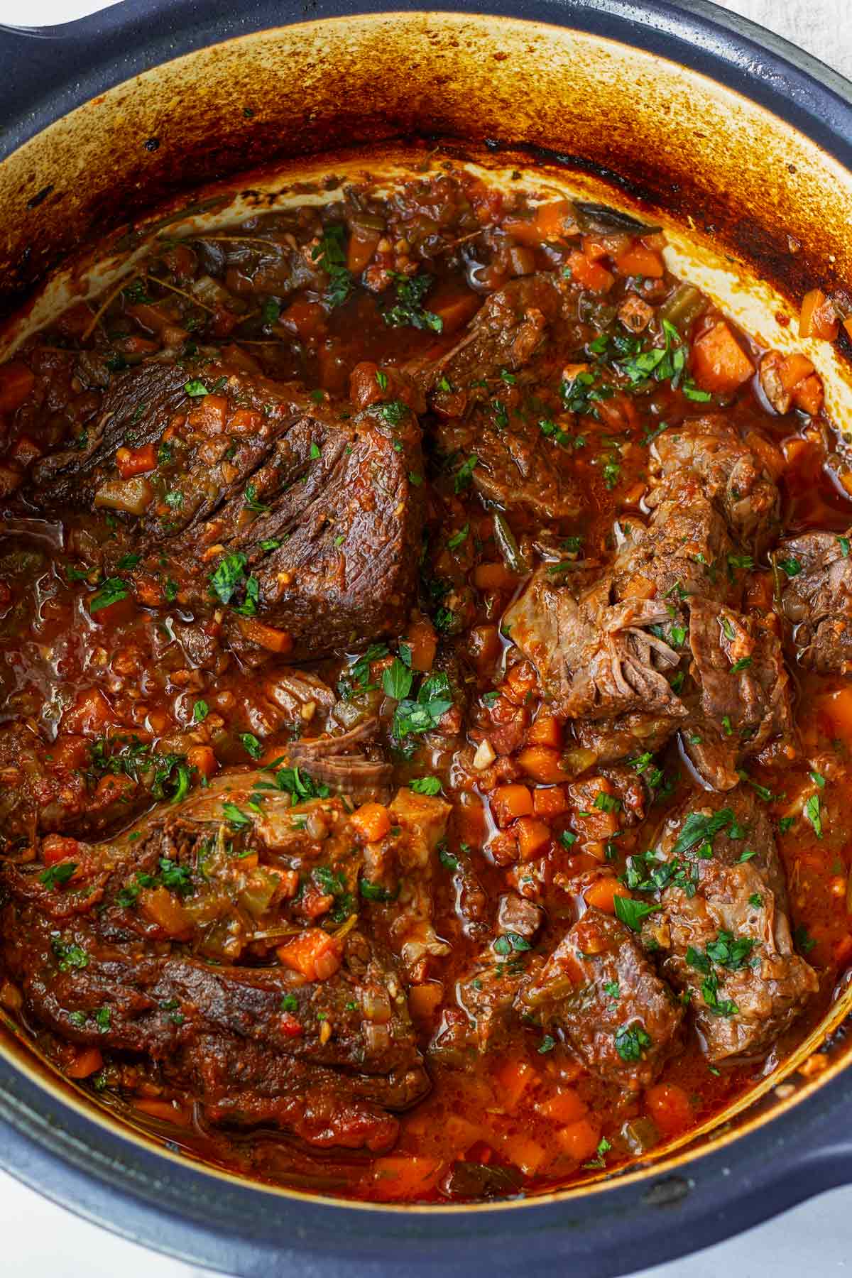 finished and garnished italian pot roast in a blue dutch oven