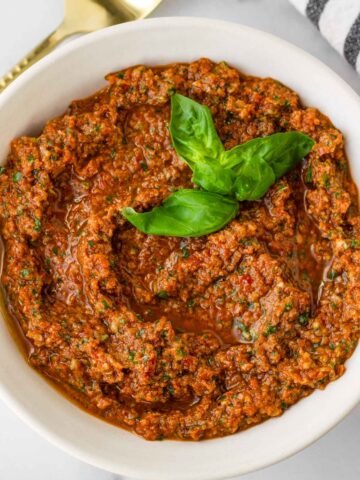 sun dried tomato pesto in a bowl with basil garnish