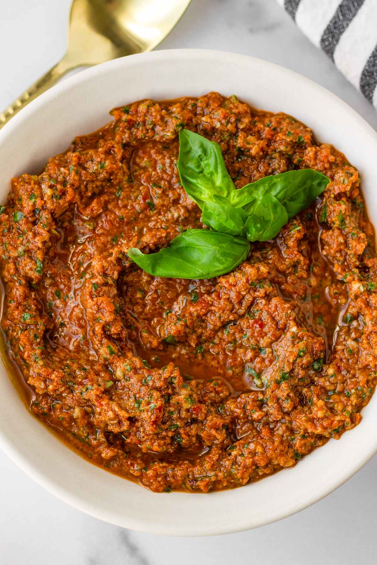 sun dried tomato pesto in a bowl with basil garnish