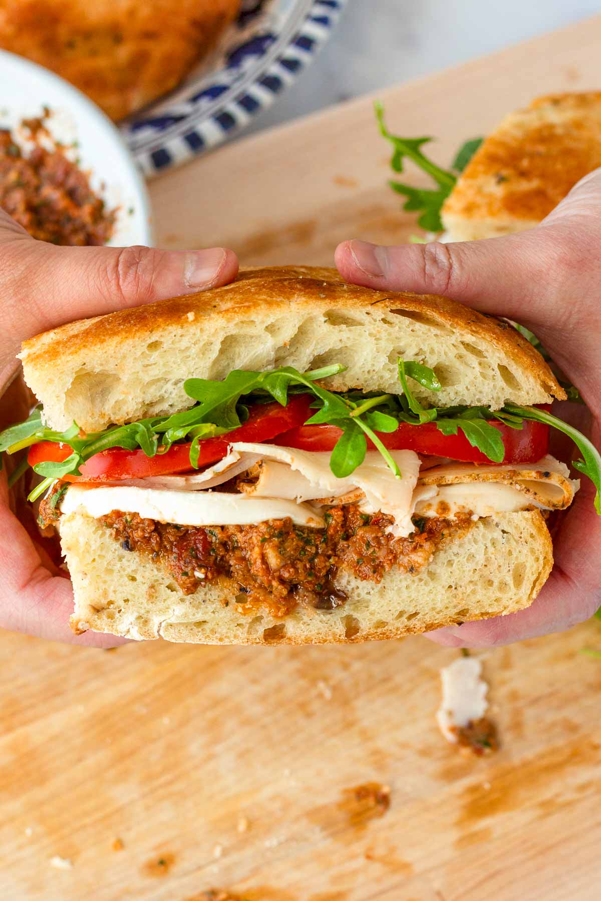 holding a sliced focaccia sandwich with shaved turkey and mozzarella
