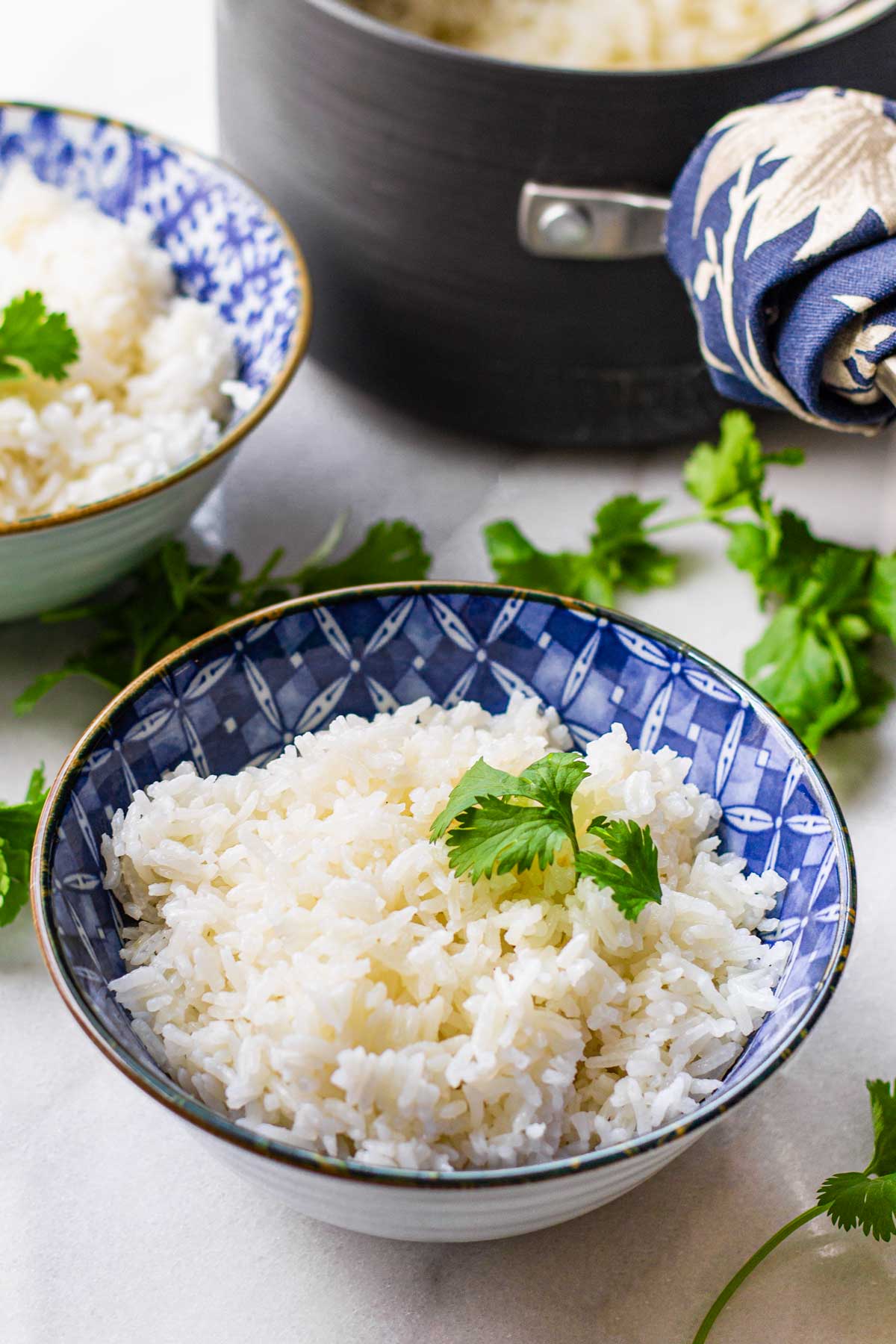 two bowls with coconut rice and the saucepan behind
