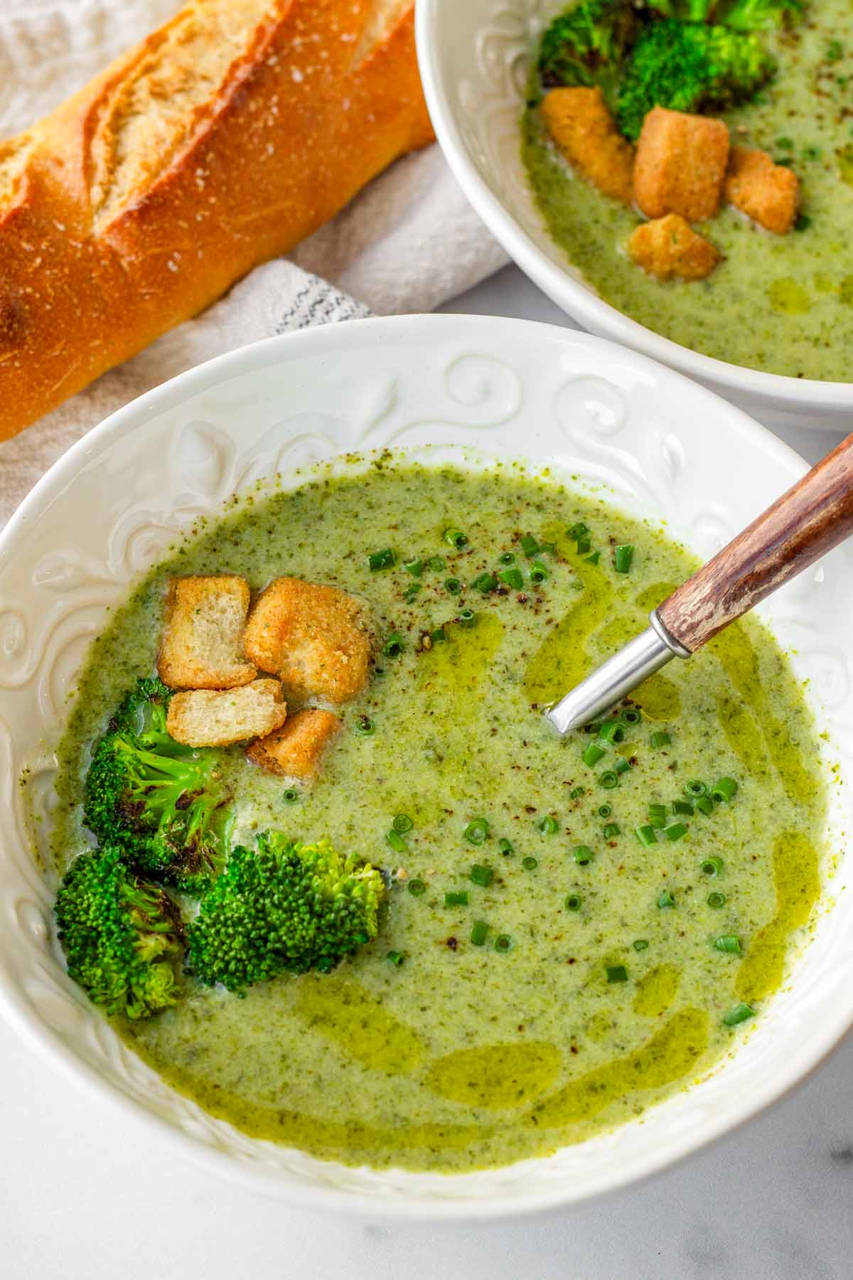 bowl of broccoli soup with croutons and baguette