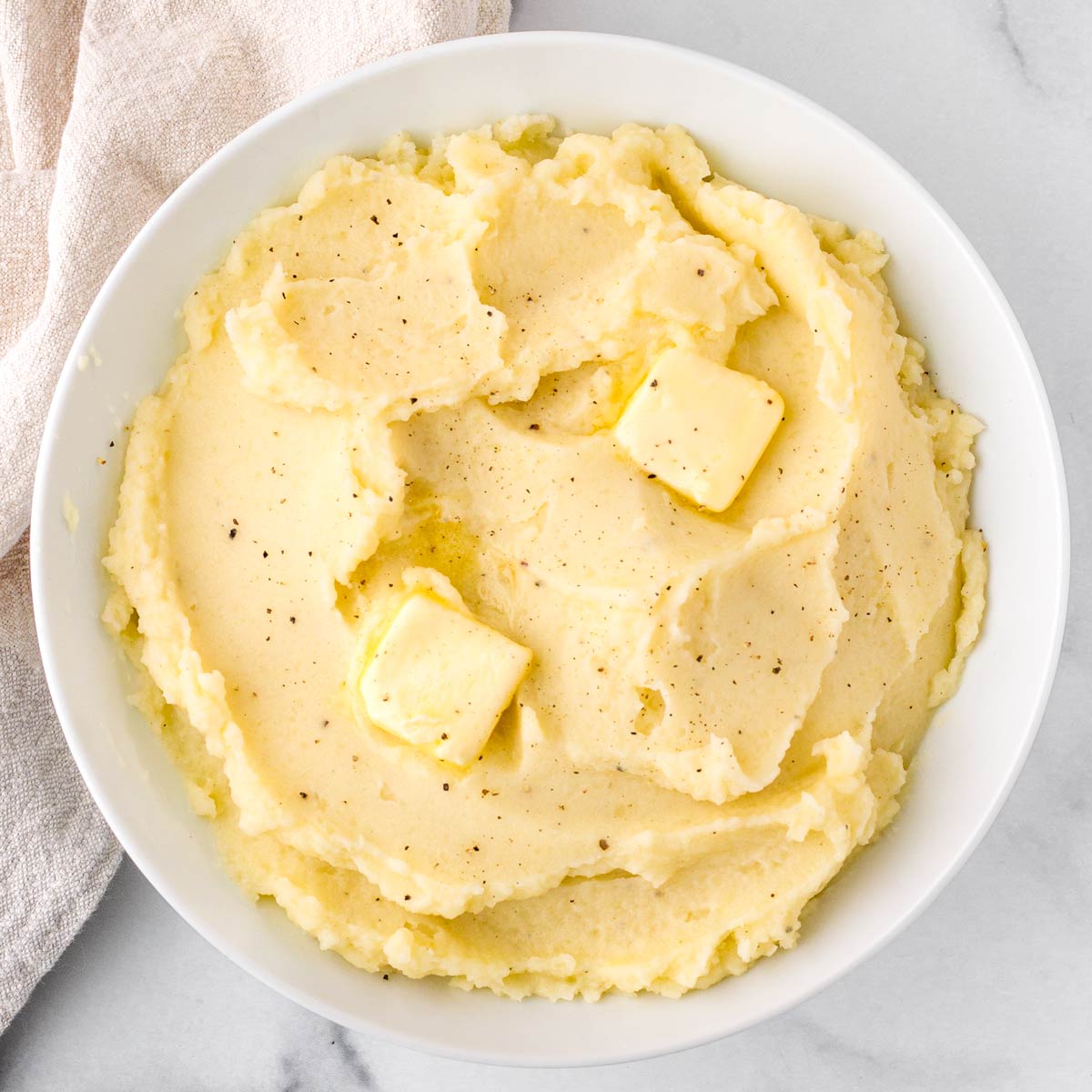 fluffy mashed potatoes in bowl with a napkin next to it