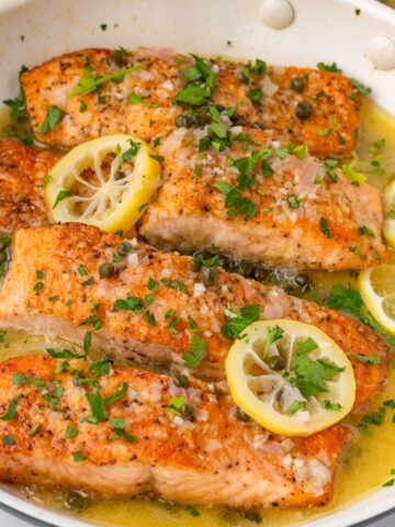 salmon piccata with capers and lemon slices on top