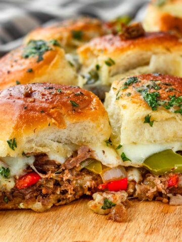 two cheesy and loaded philly cheesesteak sliders with garlic butter