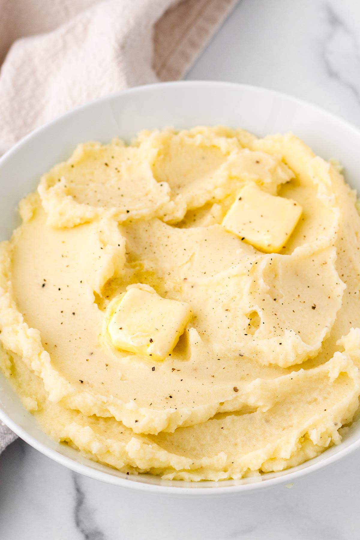 bowl with creamy and fluffy mashed potatoes topped with butter and pepper