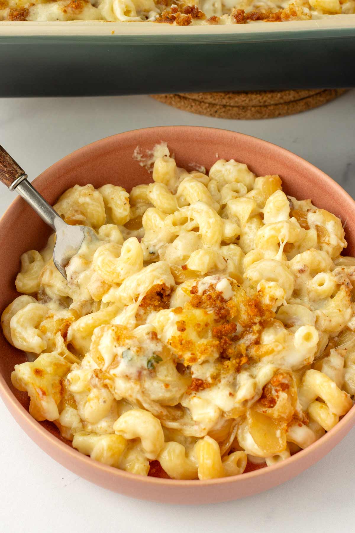 a bowl with a spoon of creamy mac and cheese