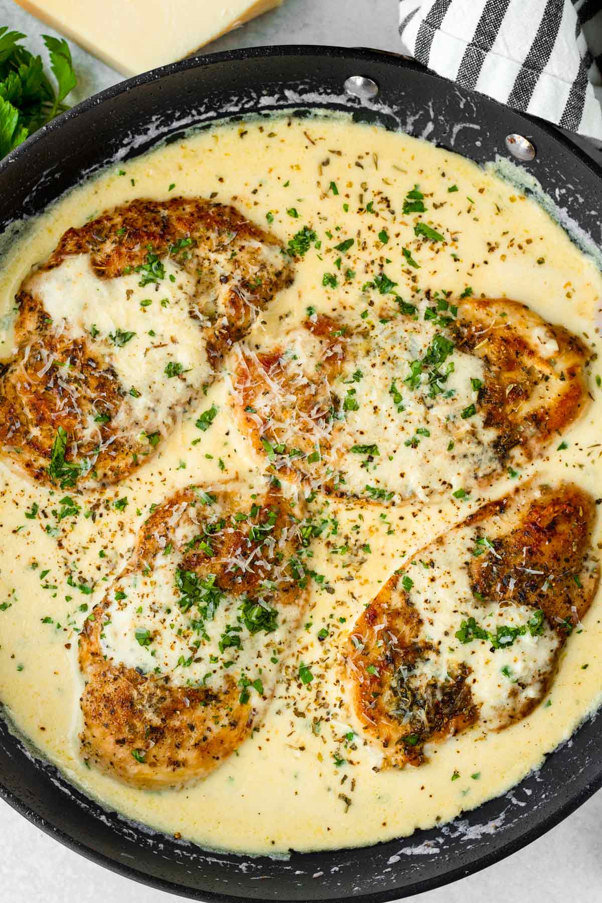 four pieces of golden brown chicken with creamy sauce and parsley garnish