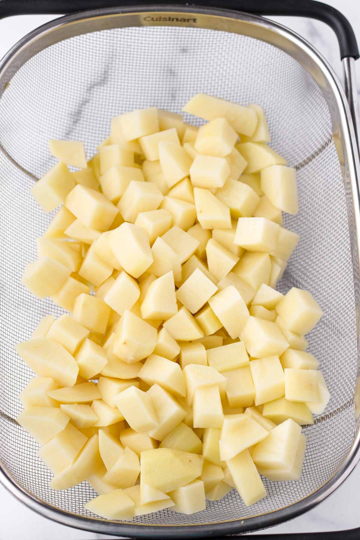 diced and peeled russet potatoes in a colander