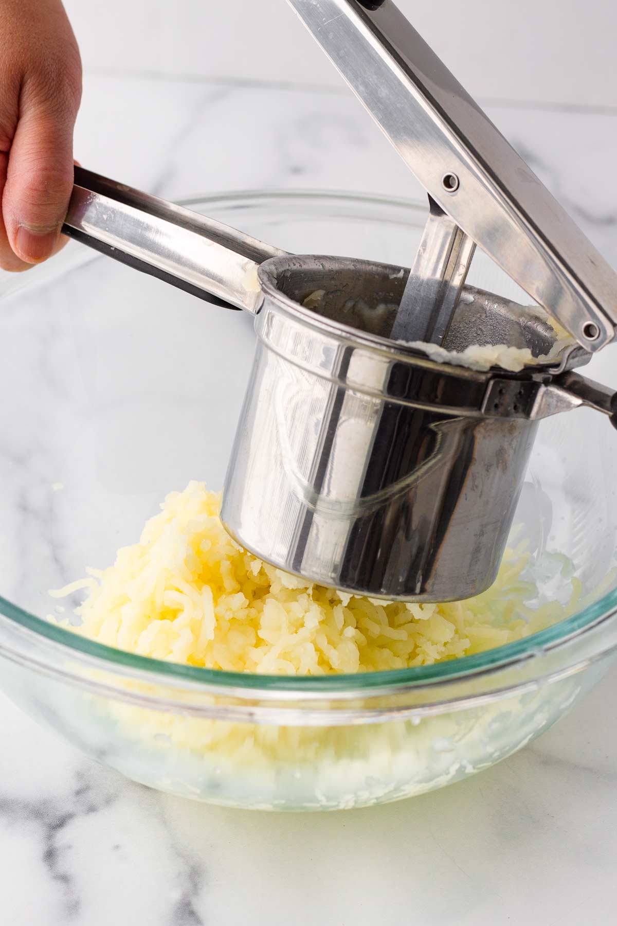 pressing cooked potatoes through a ricer