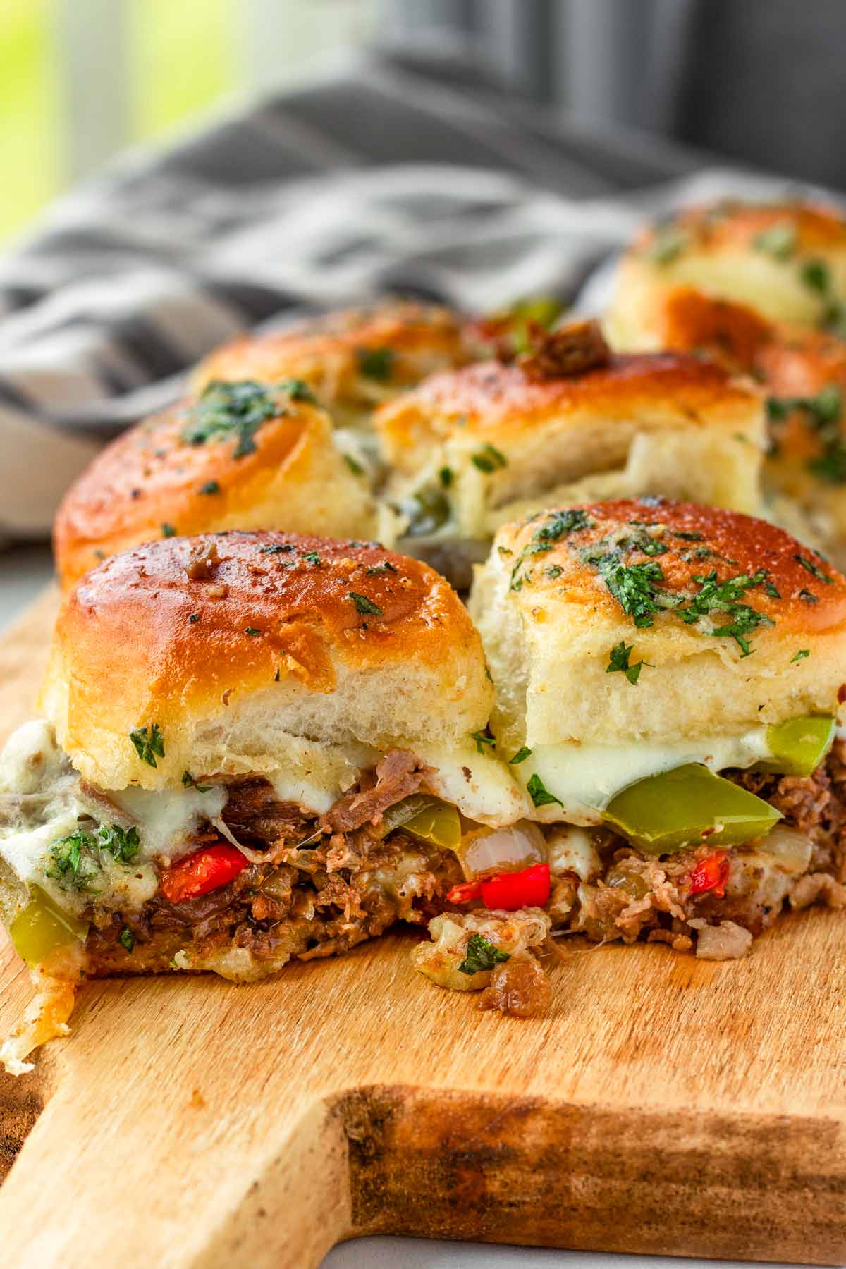 cheesy philly cheesesteak sliders on a wooden board