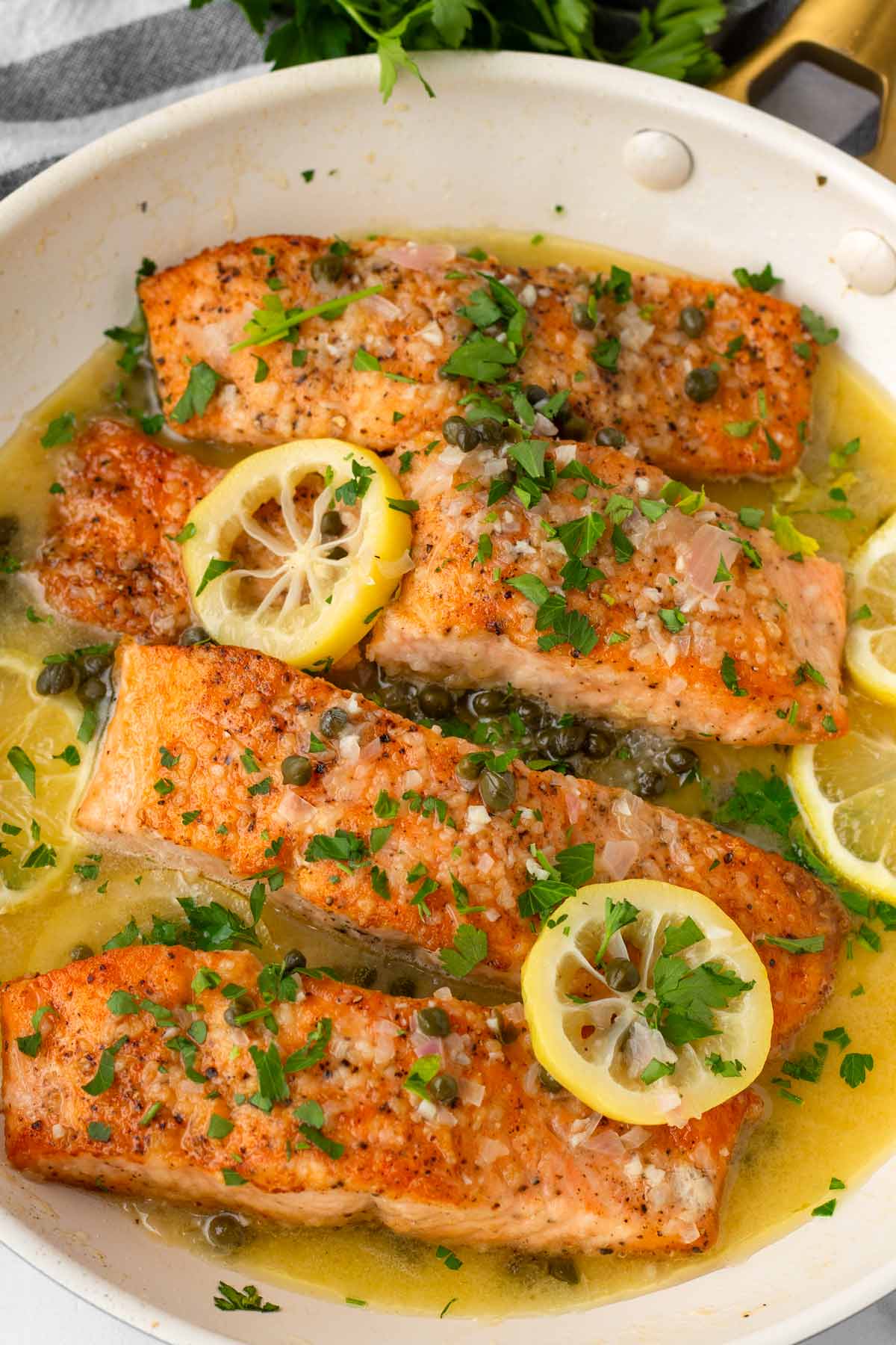four filets of salmon piccata in skillet