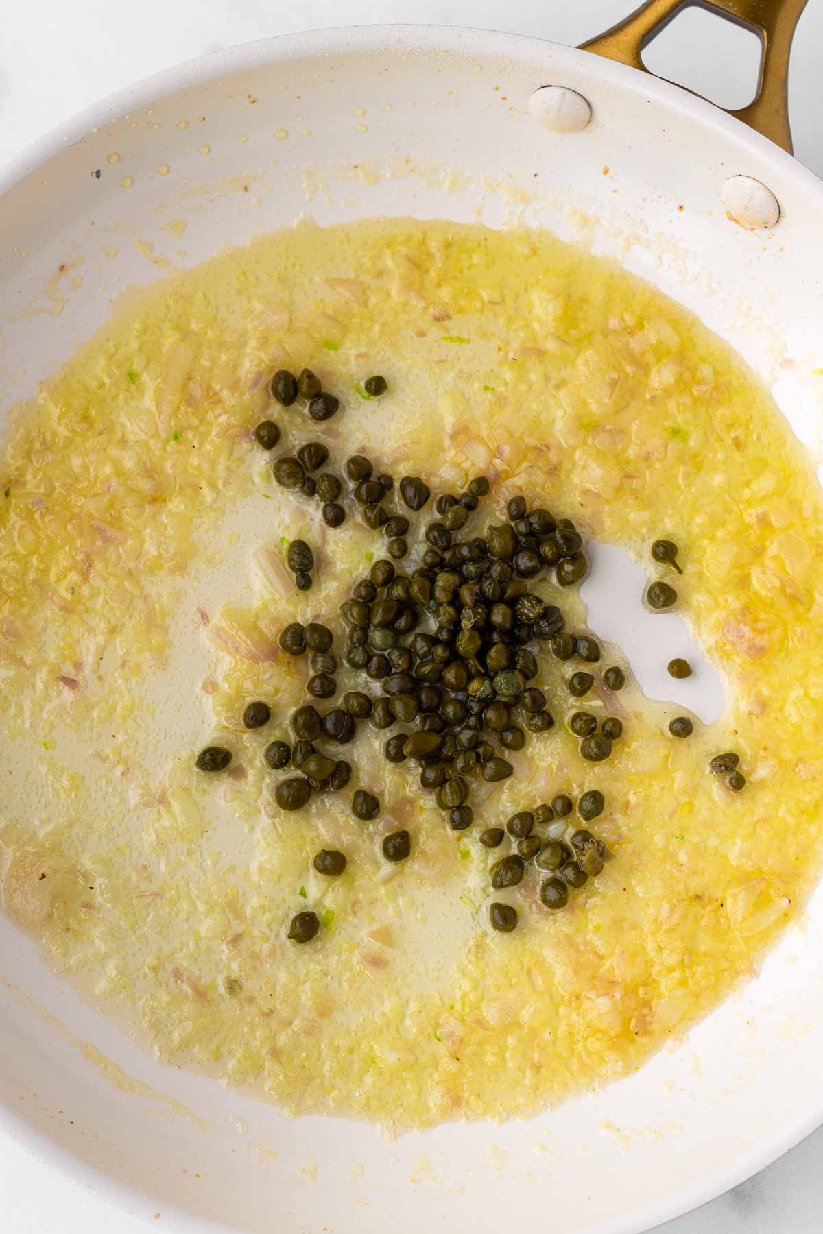aromatics and capers sauteed in a pan