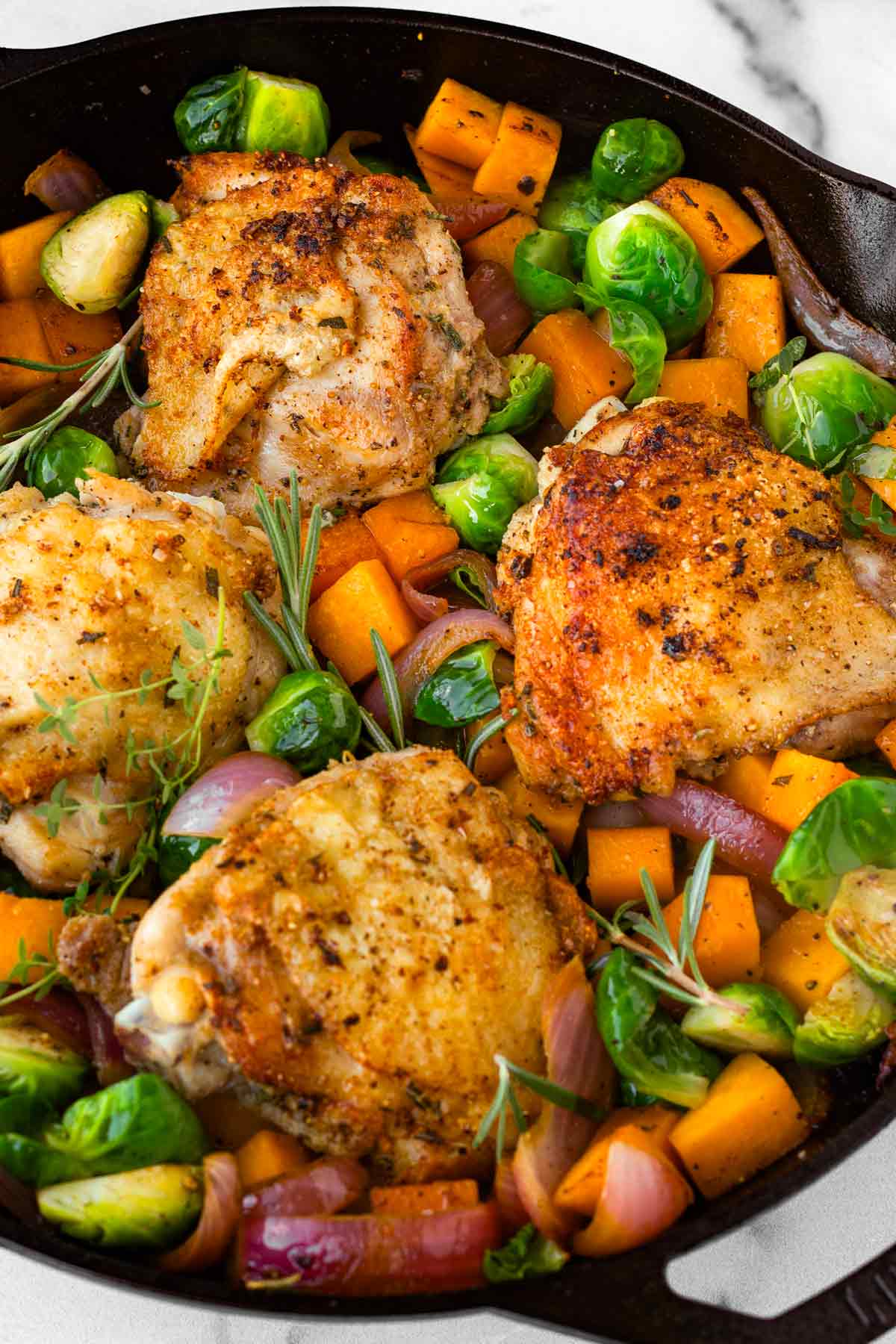 adding chicken thighs around the vegetables in skillet