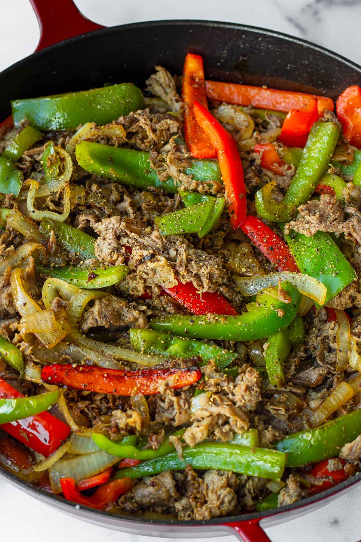 adding beef and peppers into the skillet