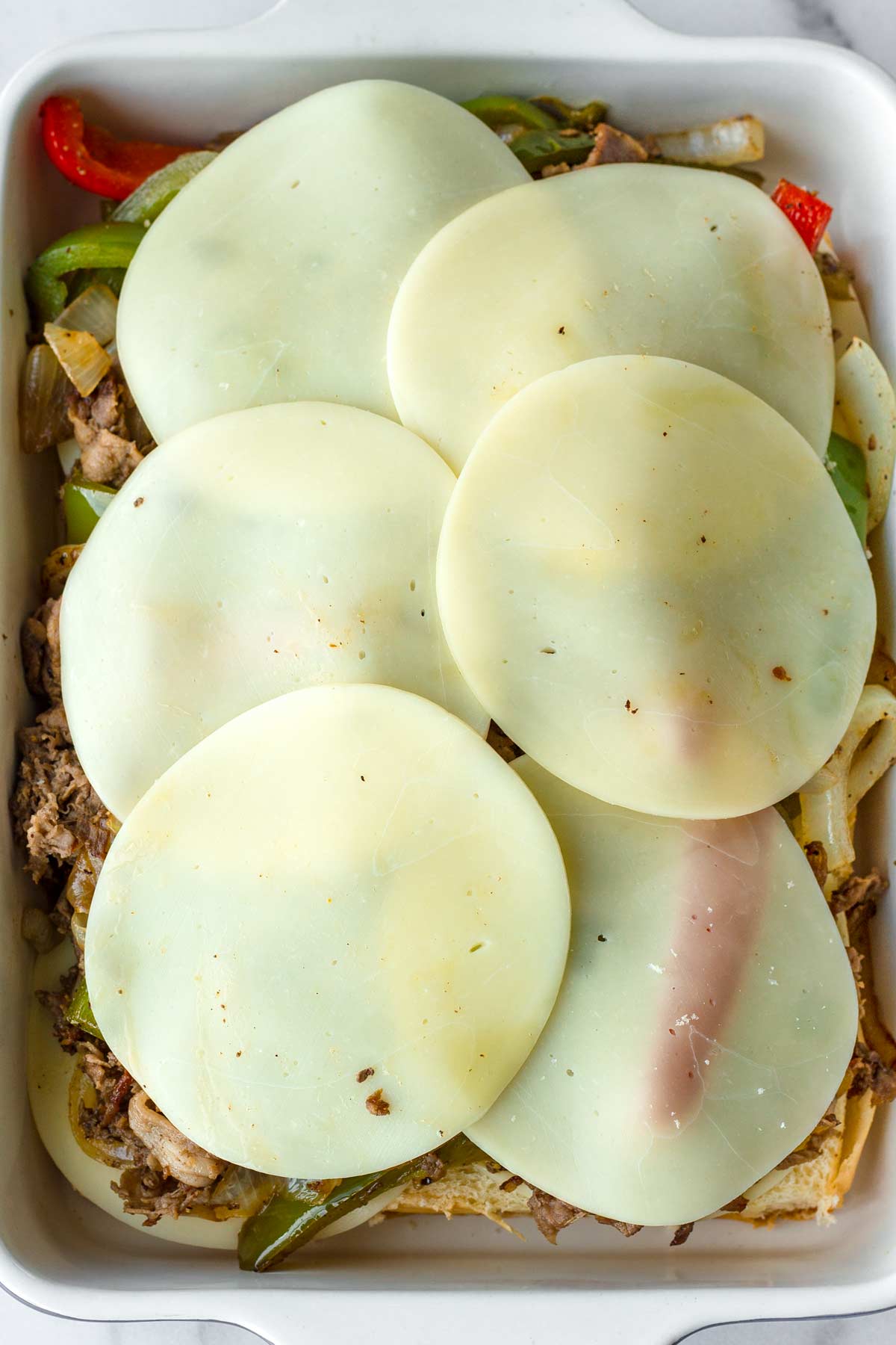 adding layers of cheese on top of the meat