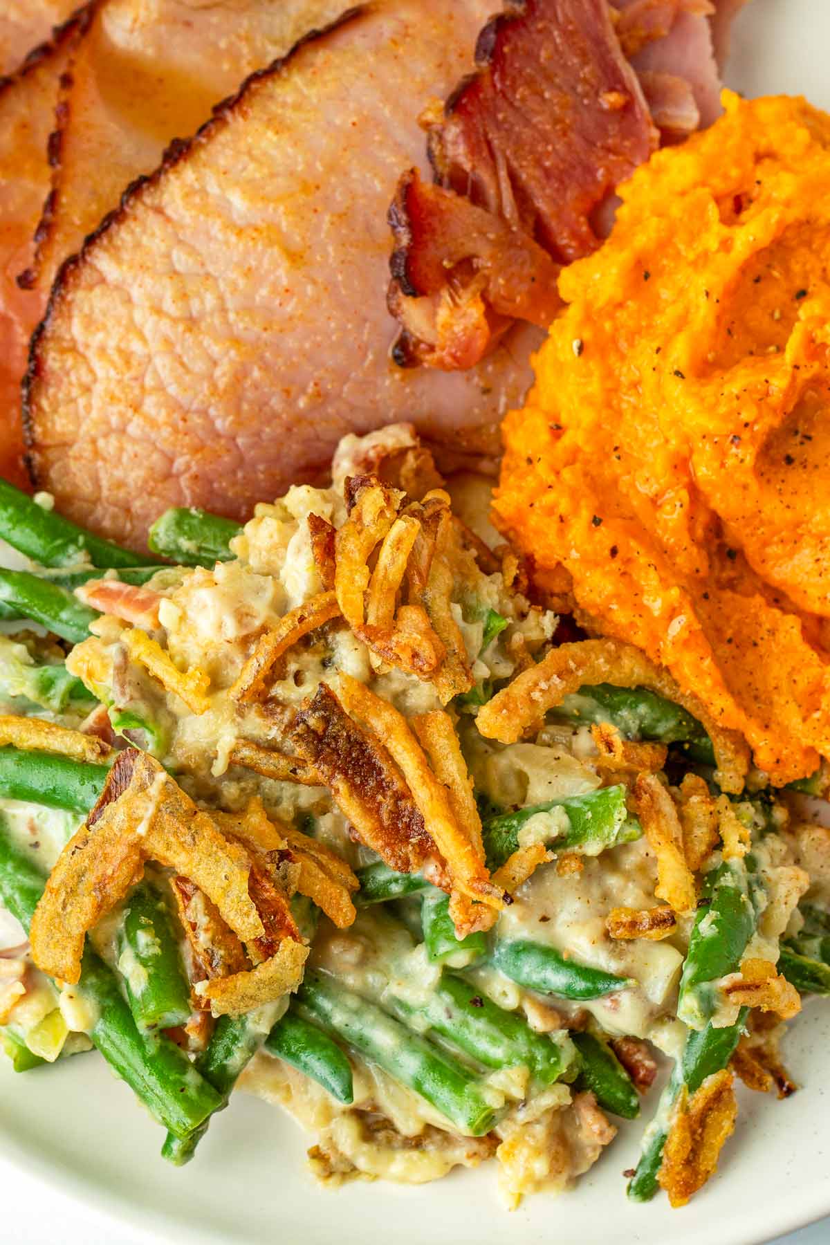 plate with green bean casserole, ham, and mashed sweet potatoes