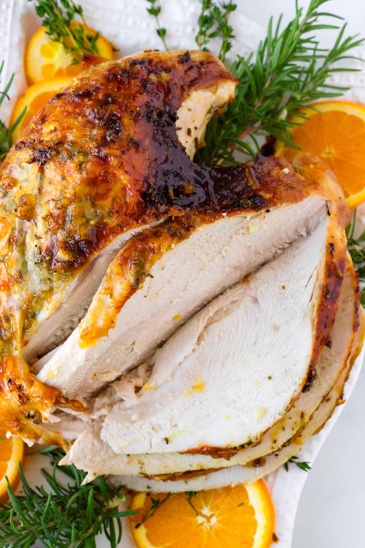 carved brined turkey breast over plate with herb and citrus decoration