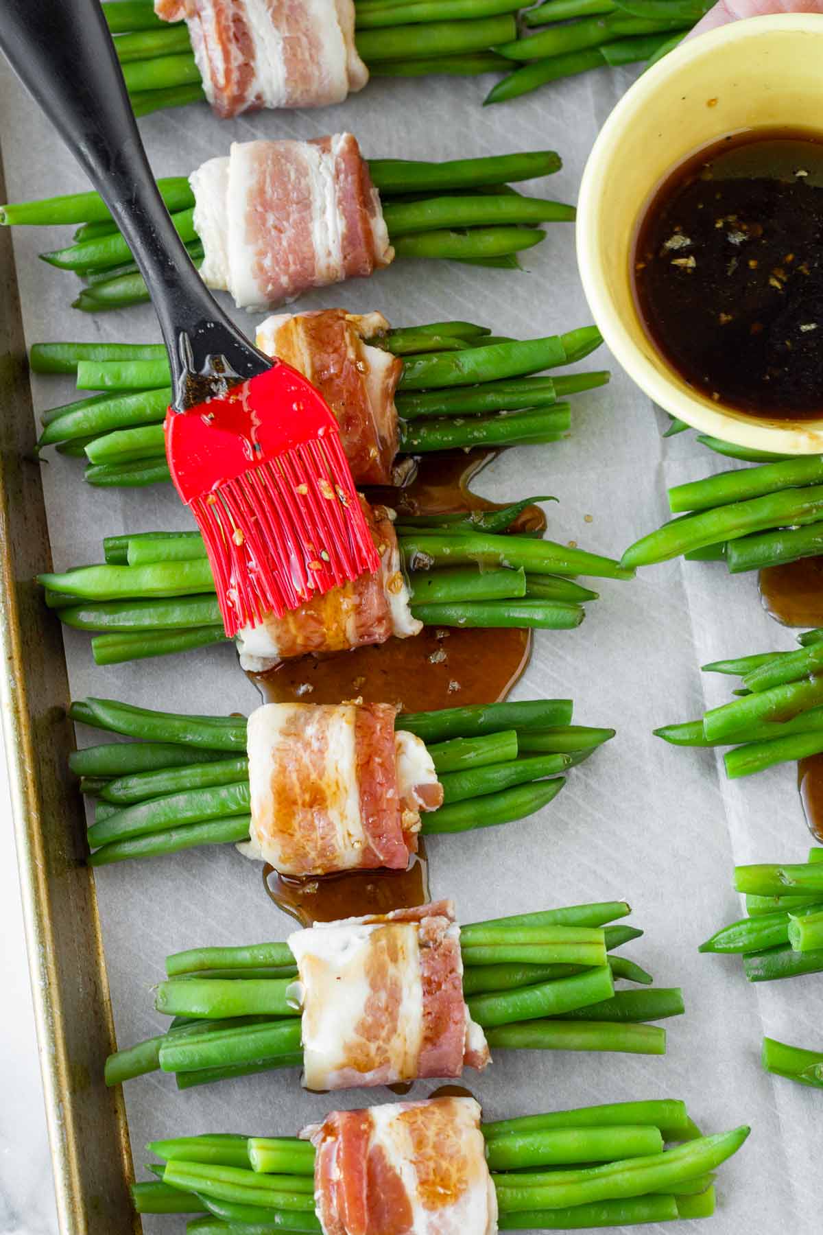brushing assembled green bean bundles with brown sugar balsamic glaze
