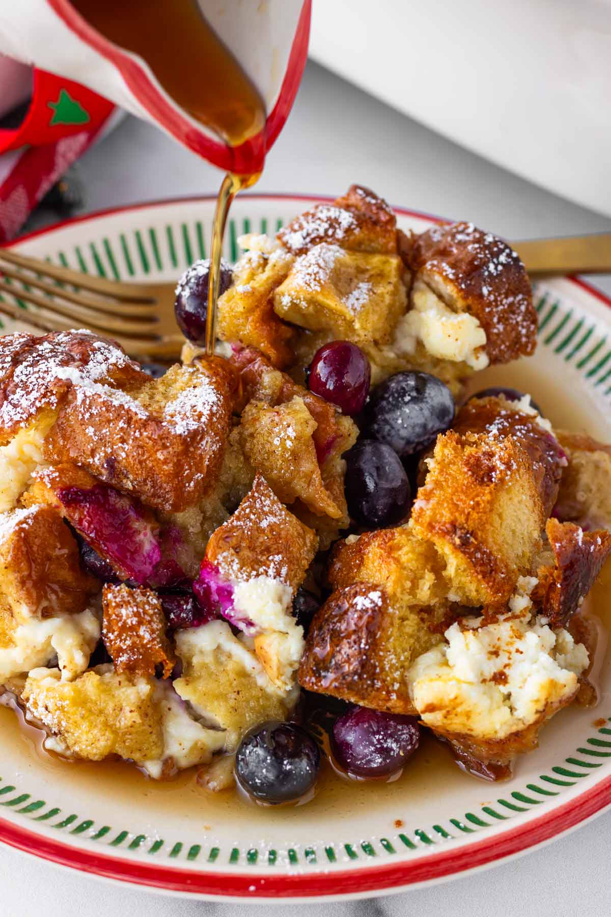 a serving of blueberry french toast casserole on plate with maple syrup drizzle