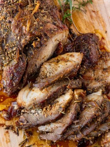 sliced golden brown pork shoulder roast on a cutting board