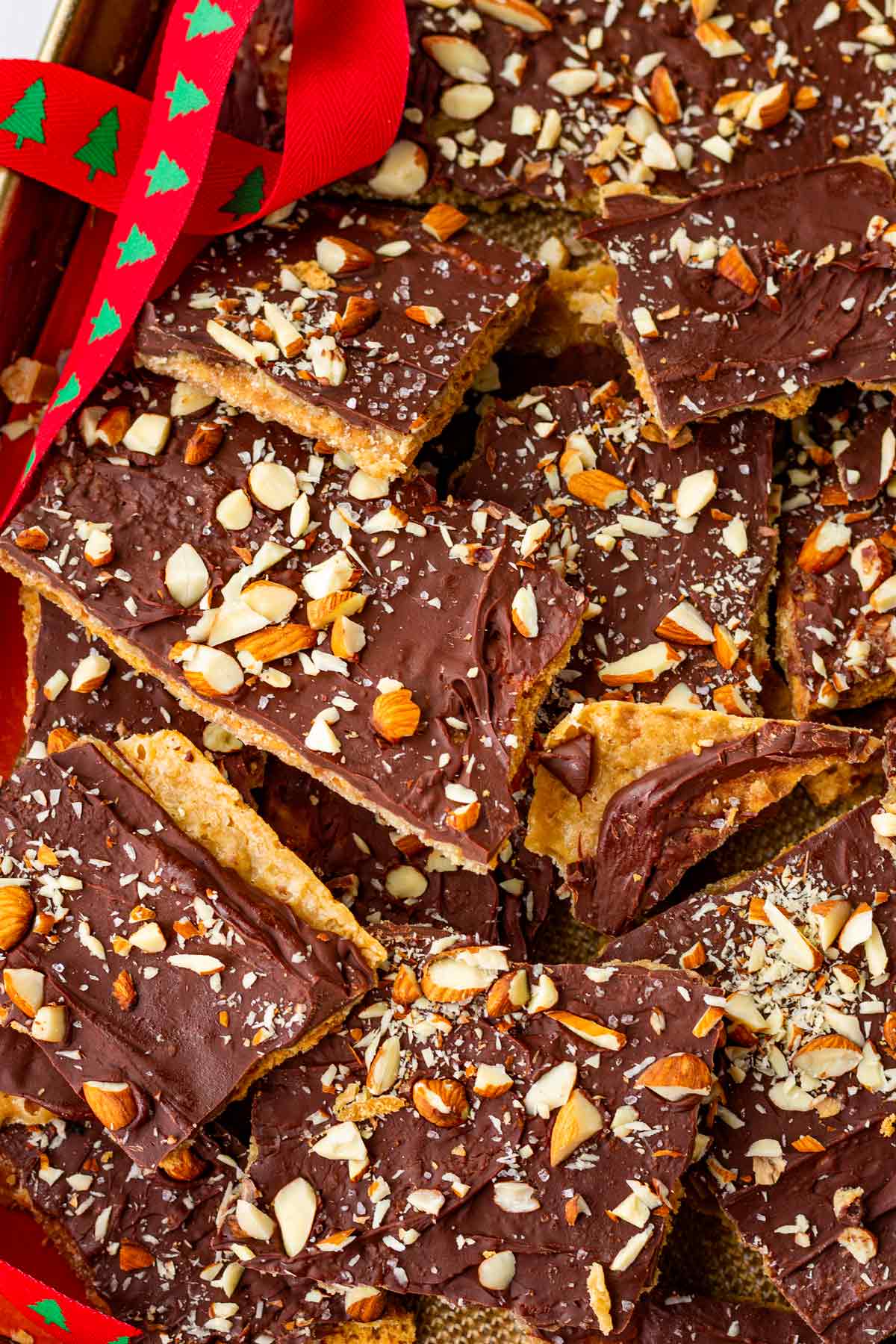 multiple pieces of graham cracker toffee piled up on a sheet pan with a decorative ribbon