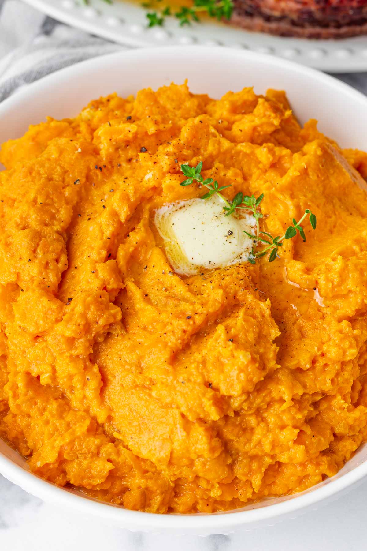 mashed sweet potatoes in bowl with butter dollop on top