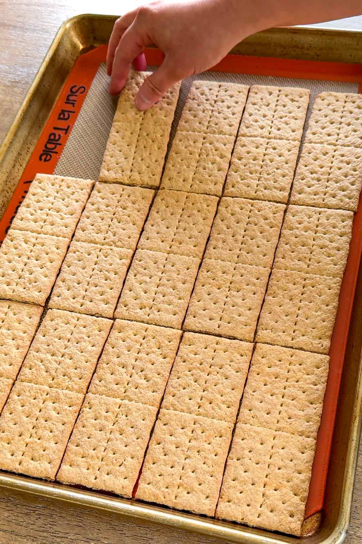 layering graham crackers on the sheet pan on top of a silpat mat