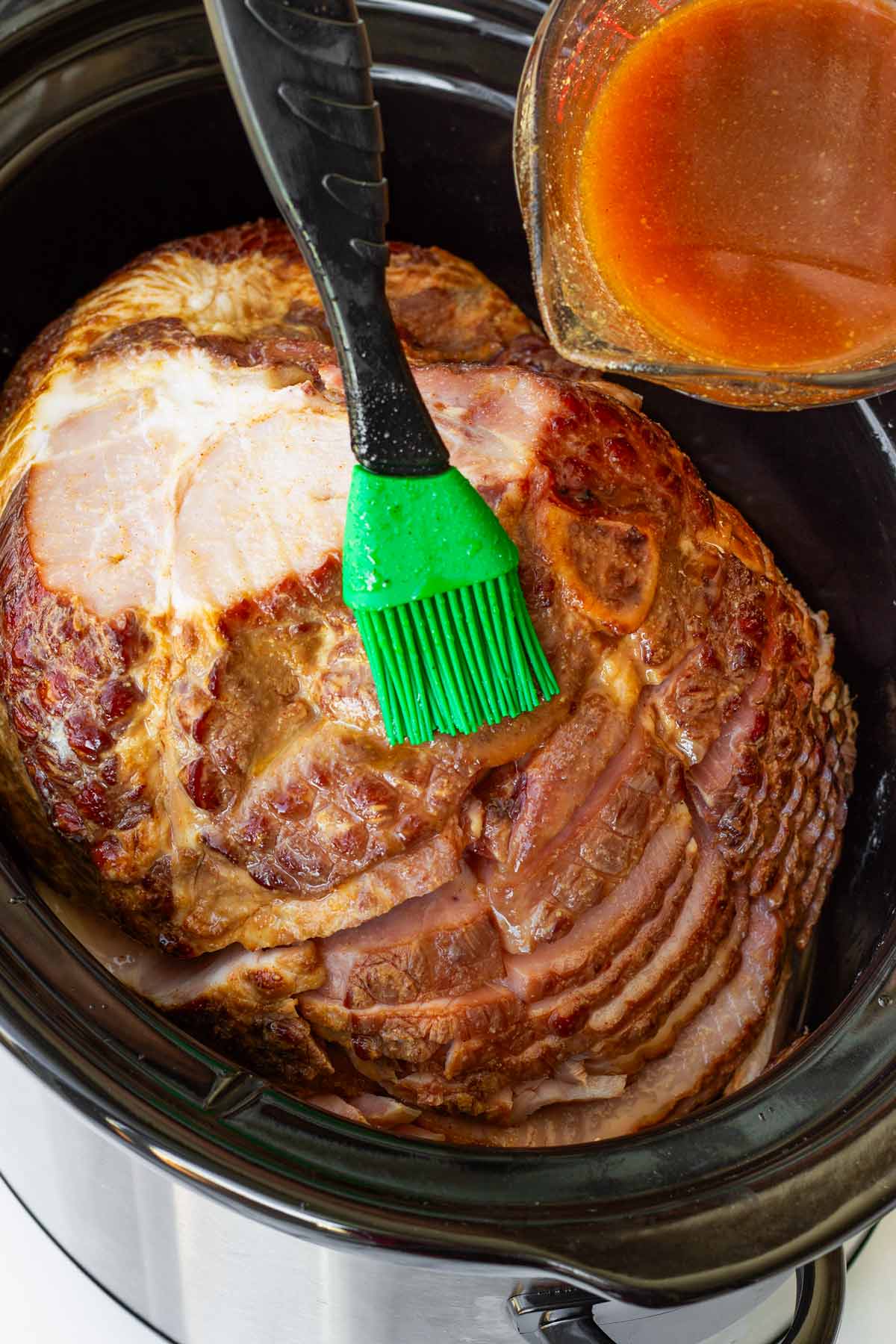 brushing ham with the glaze inside the slow cooker