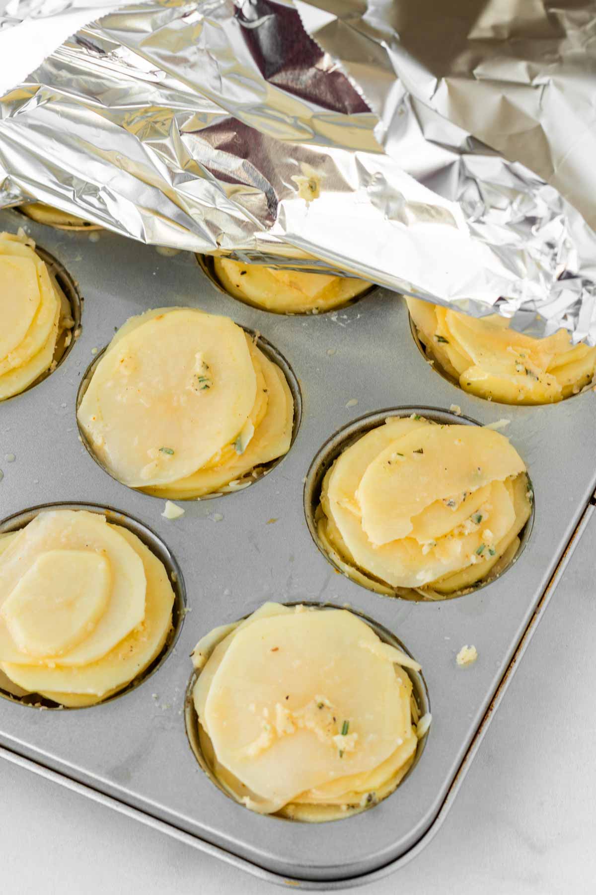 covering potato stacks in muffin tin with foil