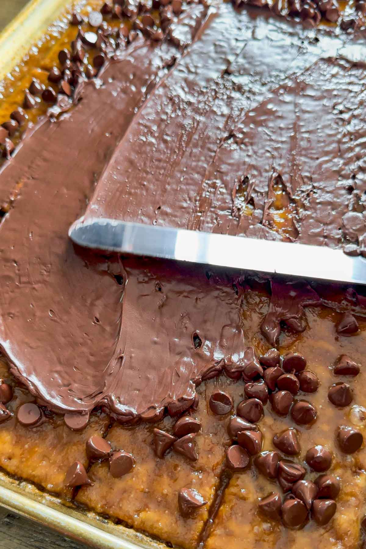 spreading melted chocolate chips on top of the caramel