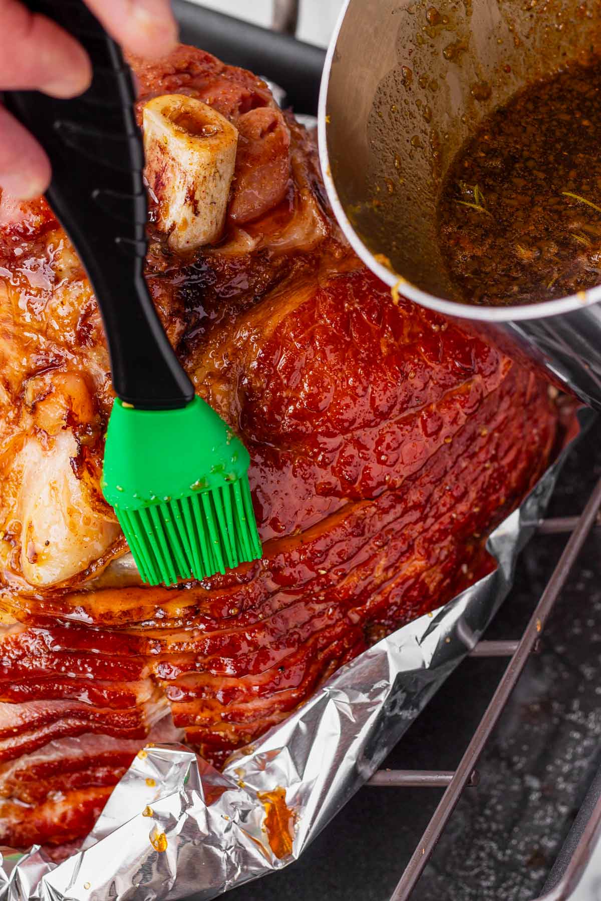 brushing the cooked ham with brown sugar glaze