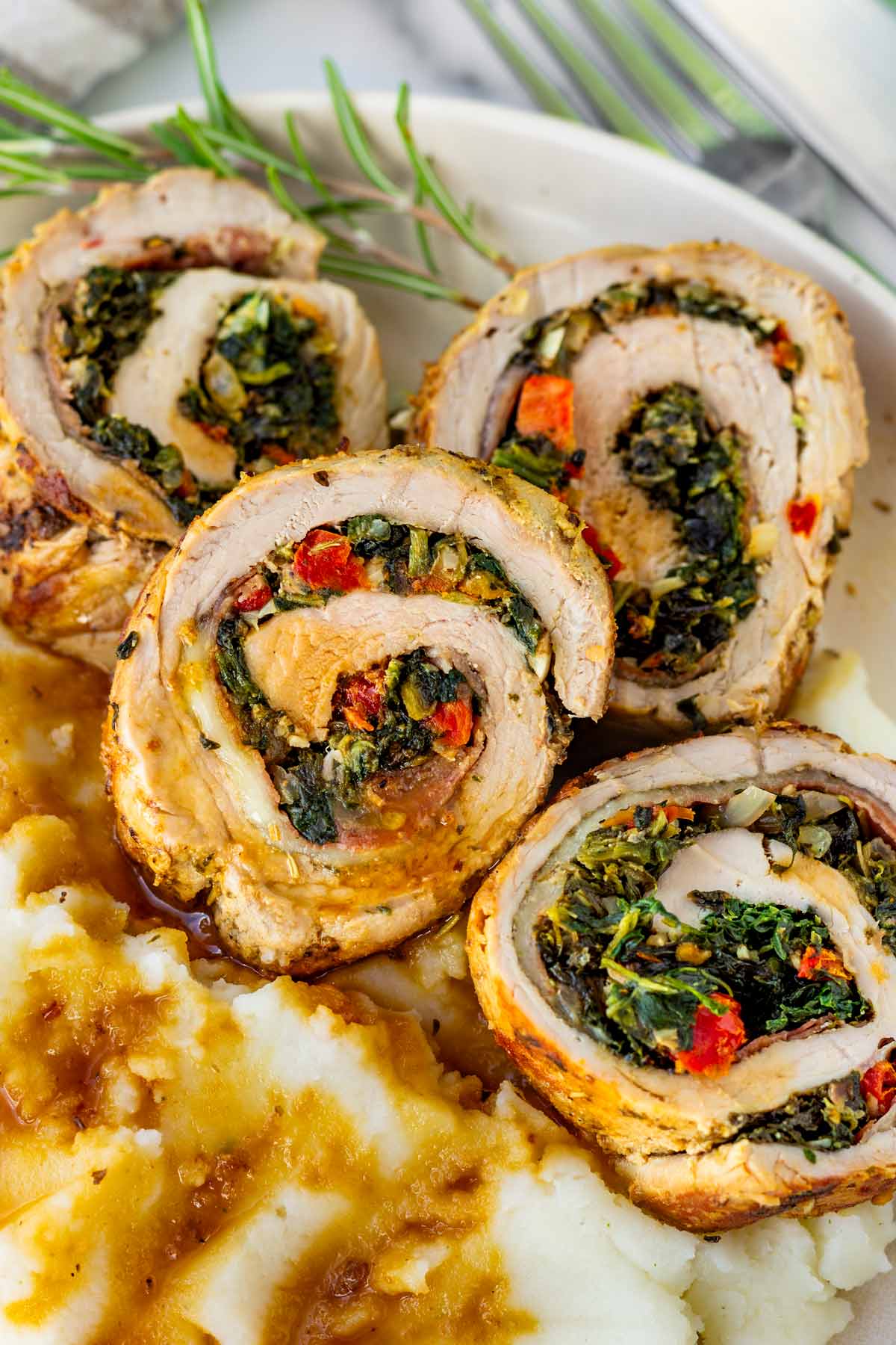 four slices of stuffed pork tenderloin on mashed potatoes