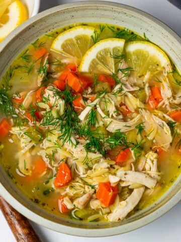 bowl of lemon chicken orzo soup with fresh dill and parsley