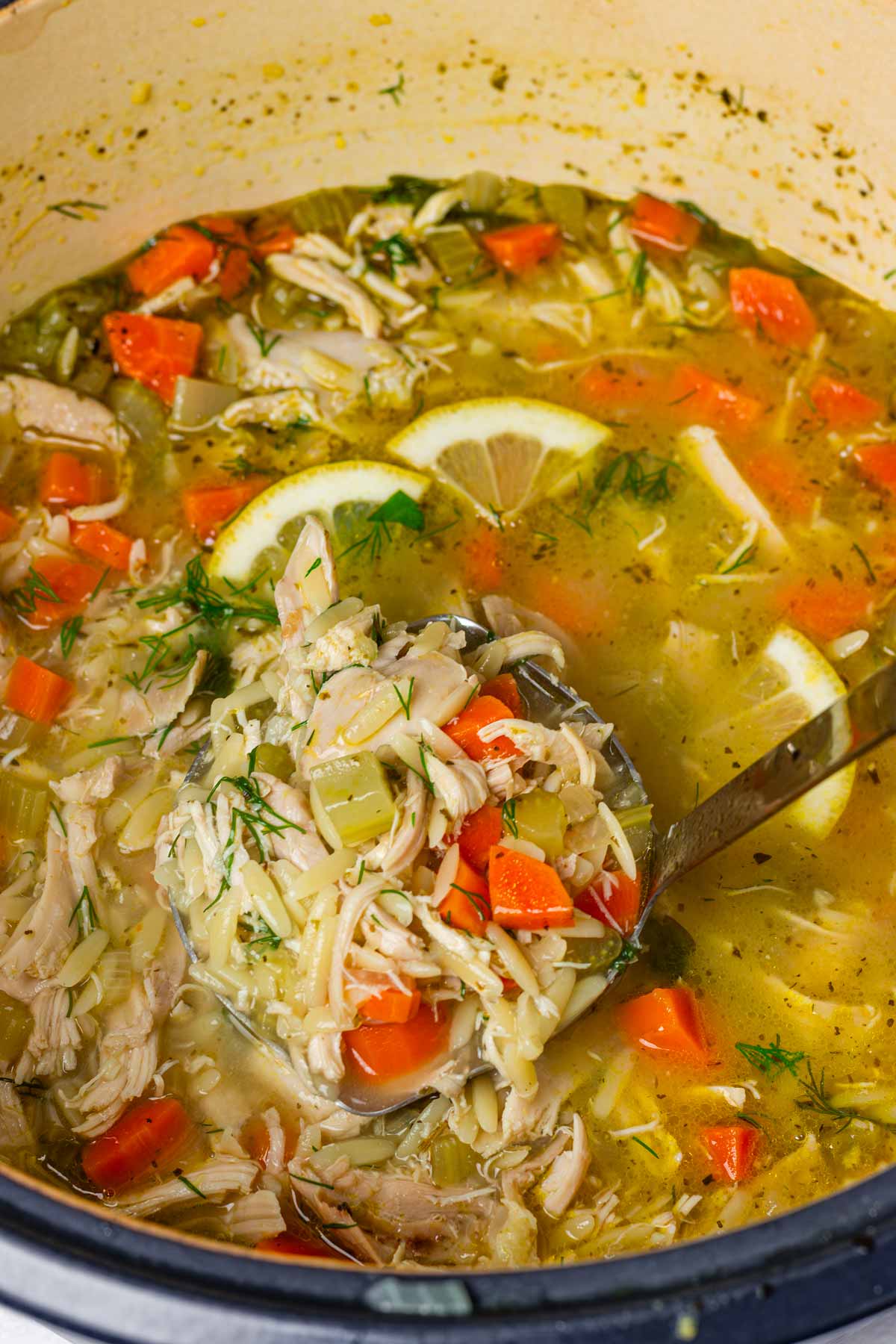 ladle of comforting lemon chicken orzo soup in a pot