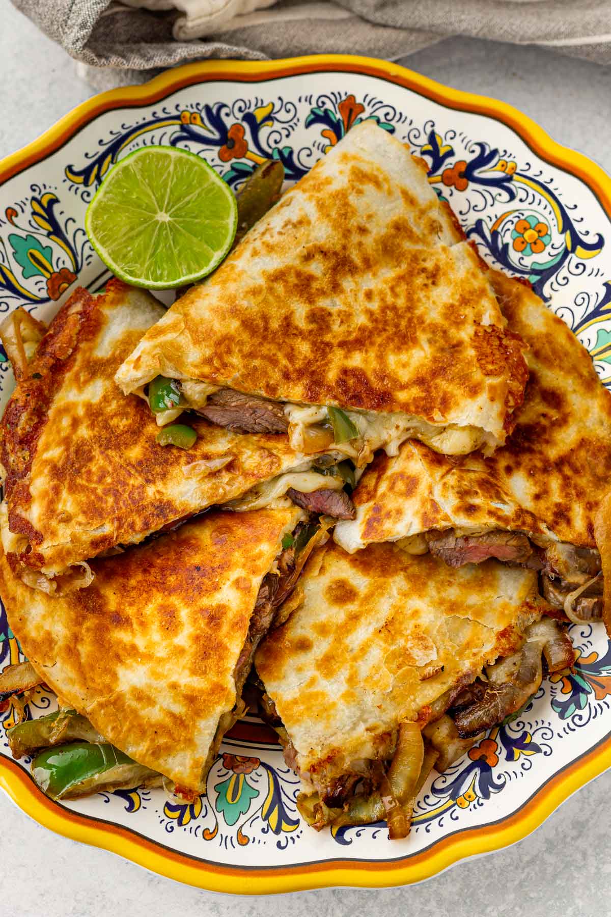 five steak quesadilla servings stacked on a decorative plate