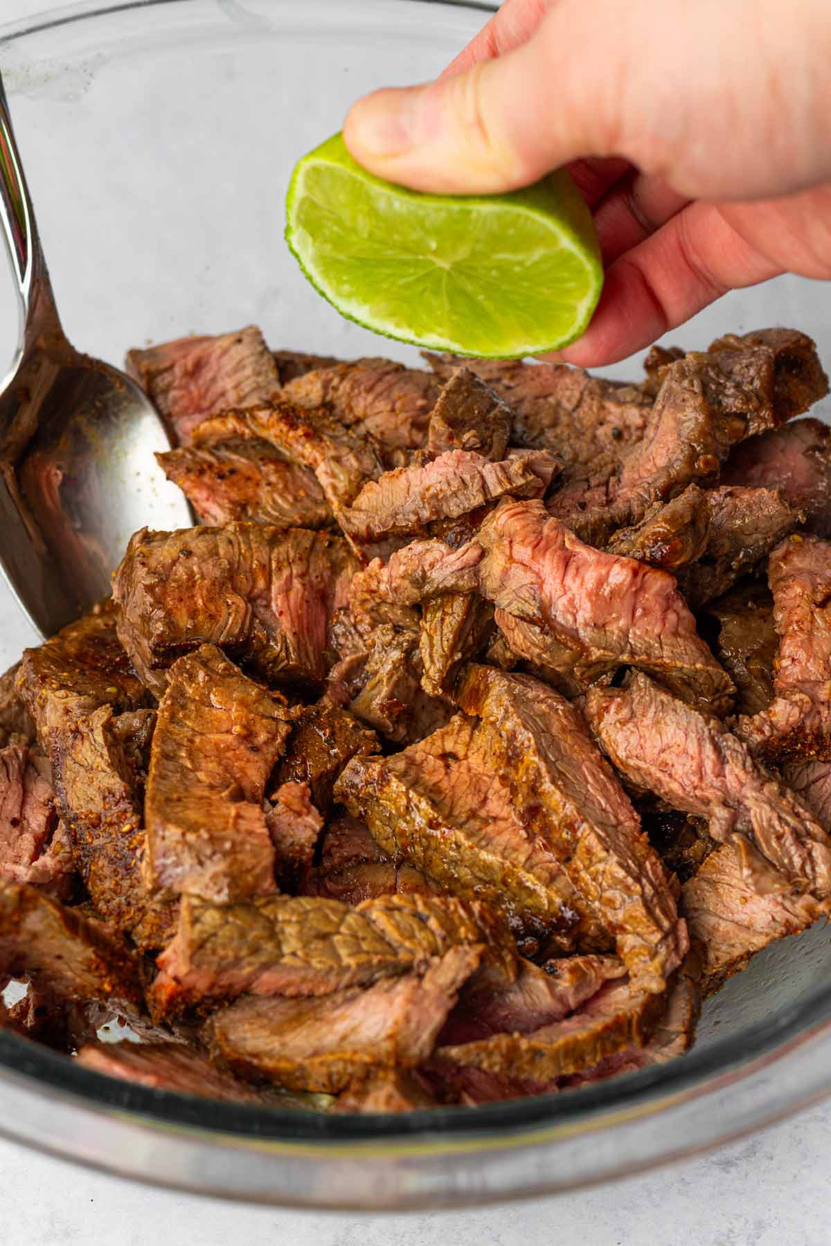 adding lime juice to cooked and sliced steak