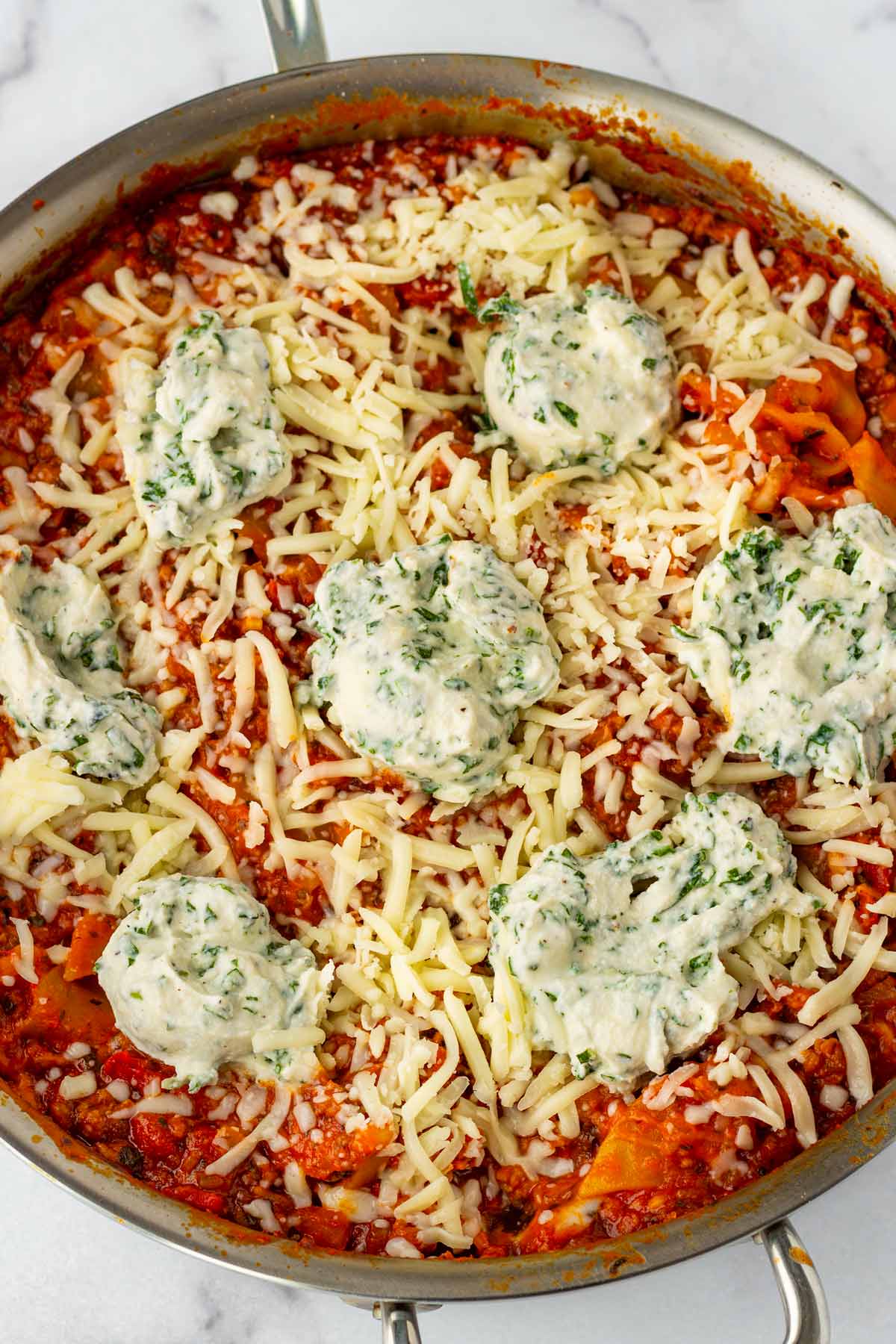 lasagna topped with ricotta basil dollops and shredded cheese